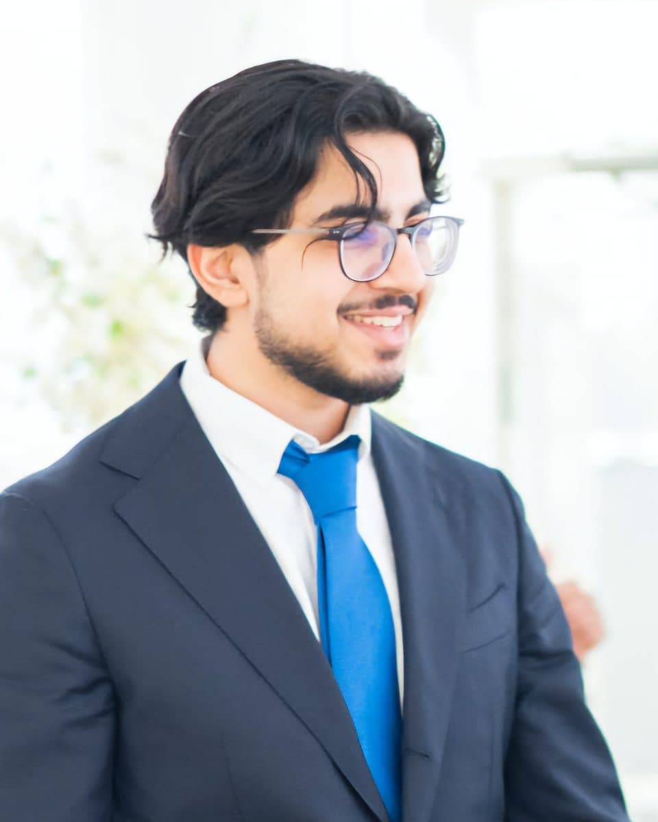 Sobhaan ul Husan in a navy suit and blue tie, smiling and looking to the right
